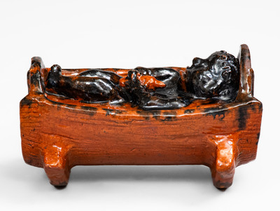 Rare and Important Figural Redware Baby-in-Cradle Bank, probably Pennsylvania