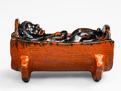 Rare and Important Figural Redware Baby-in-Cradle Bank, probably Pennsylvania